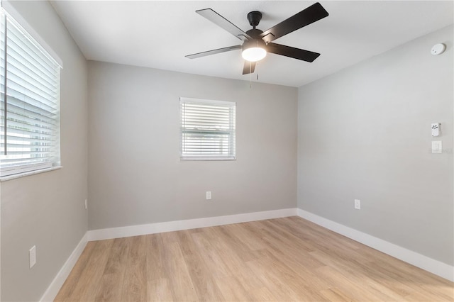 empty room featuring ceiling fan, plenty of natural light, and light wood-type flooring