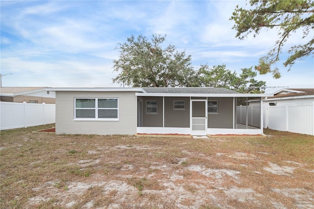 rear view of property featuring a yard and a sunroom