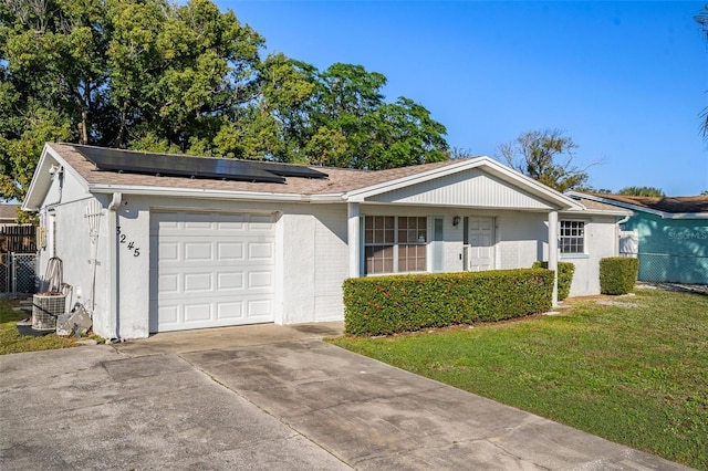 single story home with a front yard, solar panels, and a garage