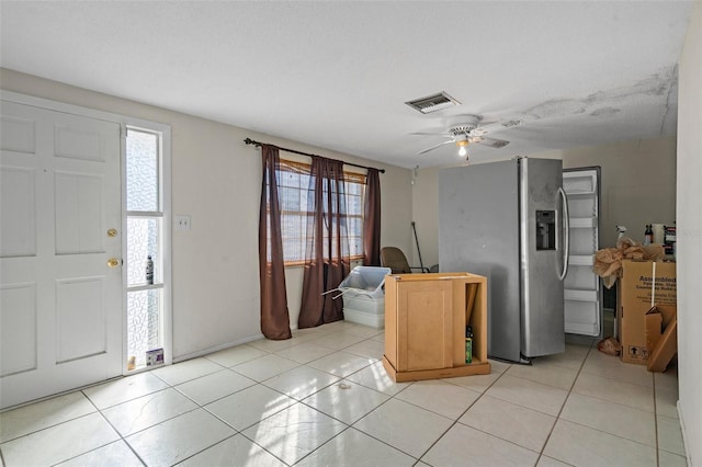 entryway featuring ceiling fan, light tile patterned flooring, and a textured ceiling