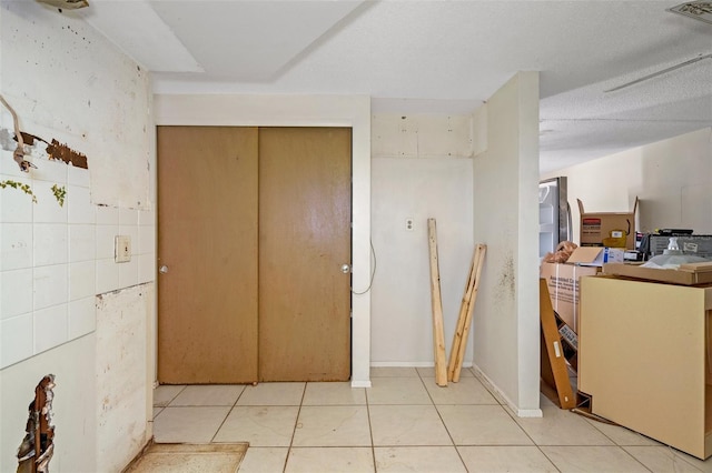 hallway with a textured ceiling and light tile patterned flooring