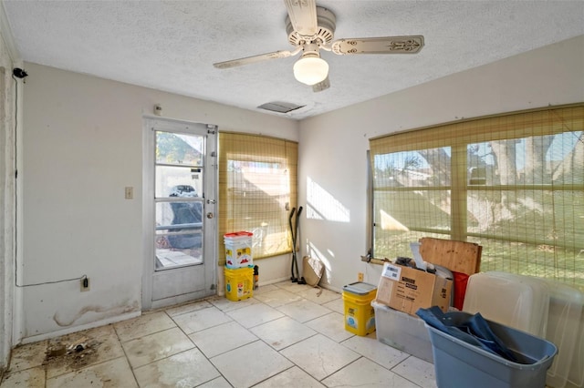 interior space with ceiling fan and a textured ceiling