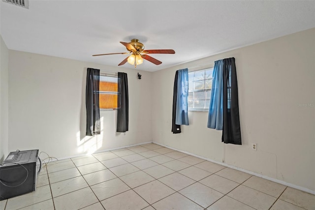 tiled spare room with ceiling fan