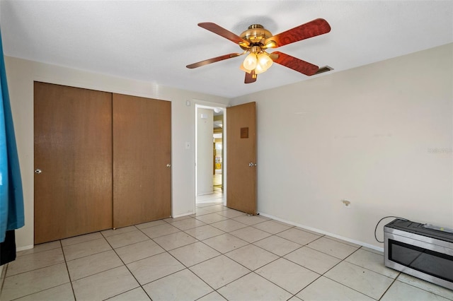 unfurnished bedroom with ceiling fan, a closet, and light tile patterned floors