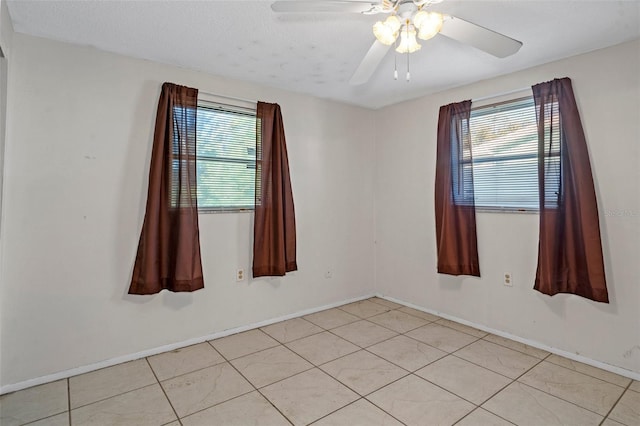 tiled empty room featuring ceiling fan and a textured ceiling