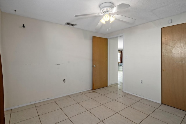 unfurnished room featuring a textured ceiling, ceiling fan, and light tile patterned flooring