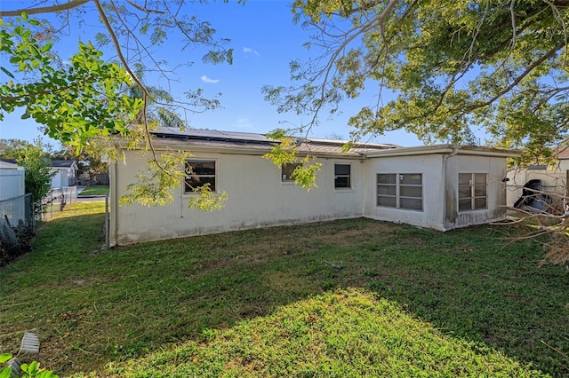 back of house featuring a lawn and solar panels