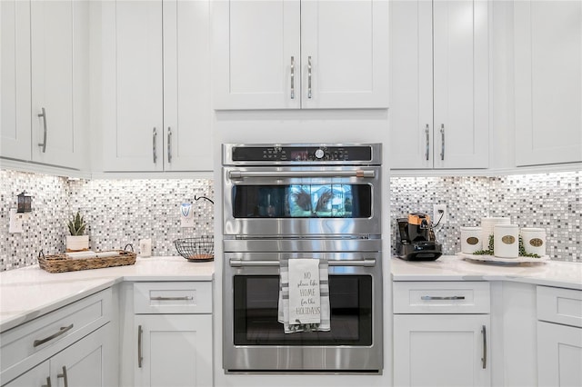 kitchen with white cabinetry, backsplash, and double oven