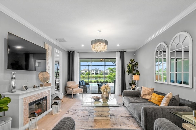 living room with a chandelier, light wood-type flooring, crown molding, and a healthy amount of sunlight