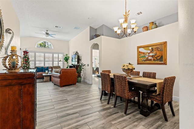 dining room featuring a textured ceiling, lofted ceiling, and ceiling fan with notable chandelier