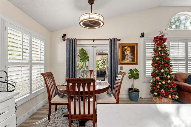 dining space with french doors, light hardwood / wood-style flooring, and lofted ceiling