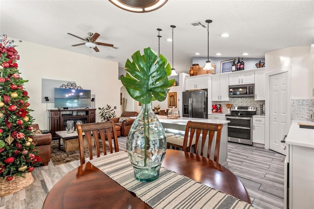 dining space with ceiling fan, vaulted ceiling, and light wood-type flooring