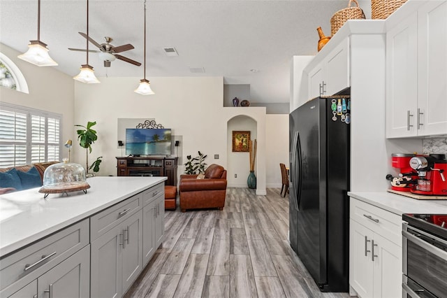 kitchen featuring ceiling fan, light hardwood / wood-style flooring, pendant lighting, black fridge with ice dispenser, and white cabinets