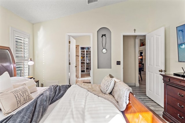 bedroom featuring lofted ceiling, a textured ceiling, and hardwood / wood-style flooring