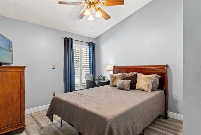 bedroom featuring a textured ceiling, vaulted ceiling, light hardwood / wood-style flooring, and ceiling fan