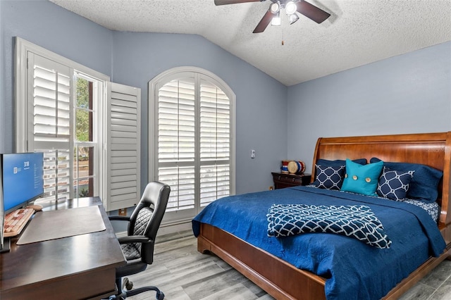 bedroom with a textured ceiling, ceiling fan, wood-type flooring, and lofted ceiling