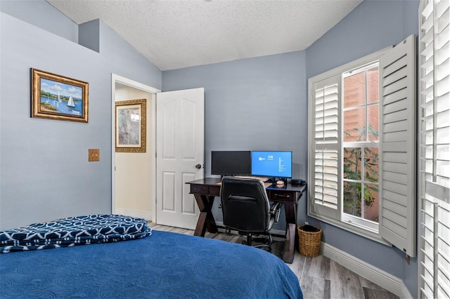 bedroom with a textured ceiling, wood-type flooring, and lofted ceiling