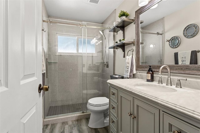 bathroom with toilet, vanity, a shower with door, and hardwood / wood-style flooring