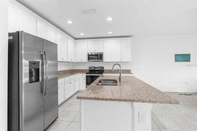 kitchen with stainless steel appliances, sink, light tile patterned floors, a center island with sink, and white cabinetry