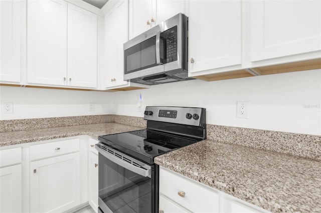 kitchen featuring appliances with stainless steel finishes, white cabinetry, and light stone counters