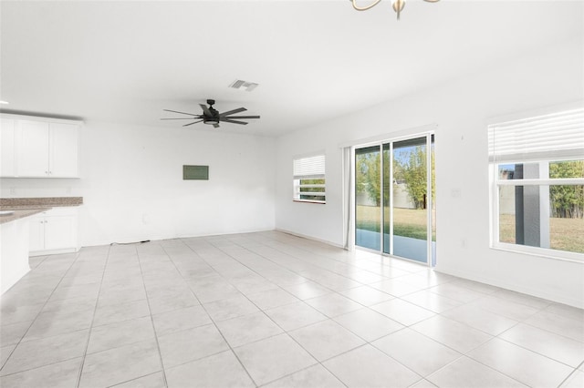 unfurnished living room with ceiling fan with notable chandelier and light tile patterned floors