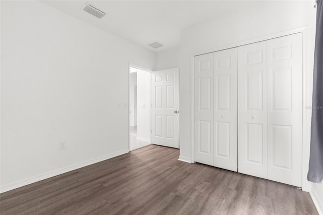 unfurnished bedroom with a closet and dark wood-type flooring