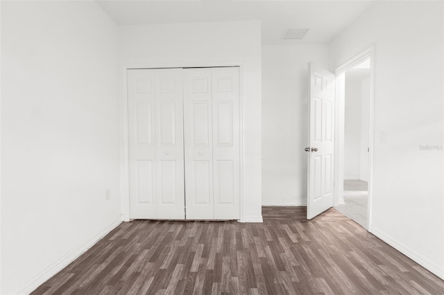 unfurnished bedroom featuring dark hardwood / wood-style floors and a closet