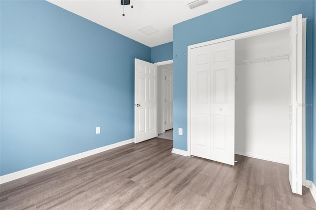 unfurnished bedroom featuring ceiling fan, a closet, and hardwood / wood-style floors