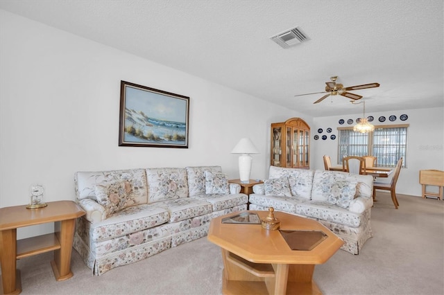 living room featuring a textured ceiling, ceiling fan, and light carpet