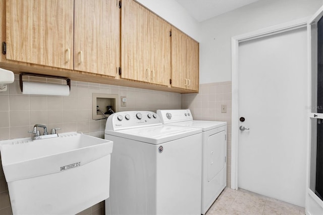 laundry room with cabinets, sink, washing machine and dryer, tile walls, and light tile patterned flooring