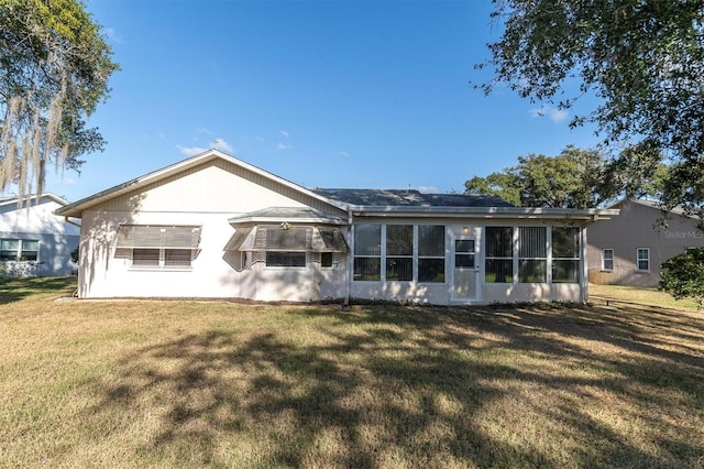 rear view of house with a sunroom and a lawn