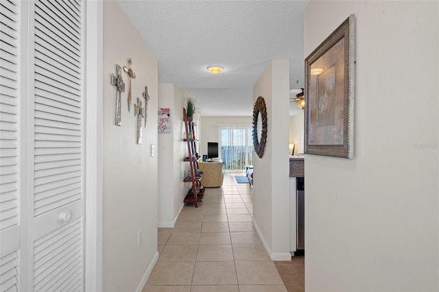 hallway featuring light tile patterned flooring and a textured ceiling