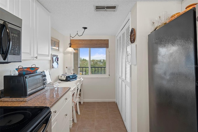 kitchen with white cabinets, hanging light fixtures, light stone countertops, light tile patterned floors, and a textured ceiling