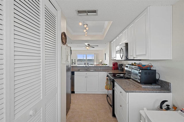 kitchen with white cabinets, a textured ceiling, stainless steel appliances, and a tray ceiling