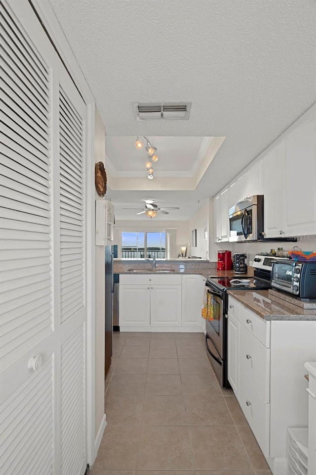 kitchen with a tray ceiling, kitchen peninsula, white cabinets, and appliances with stainless steel finishes