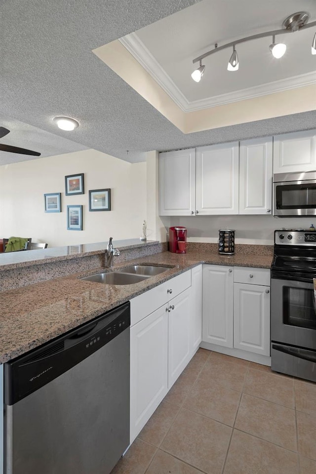 kitchen featuring appliances with stainless steel finishes, ornamental molding, sink, light tile patterned floors, and white cabinets