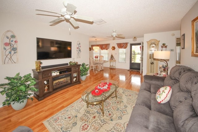 living room with a textured ceiling, ceiling fan, wood finished floors, and visible vents