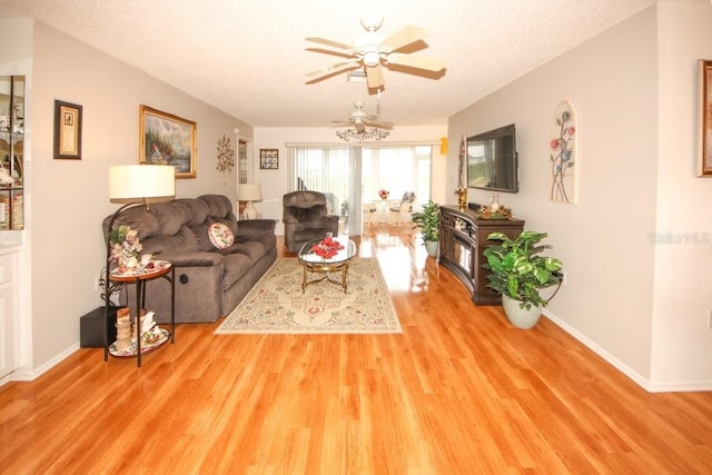 living area with a textured ceiling, wood finished floors, a ceiling fan, and baseboards