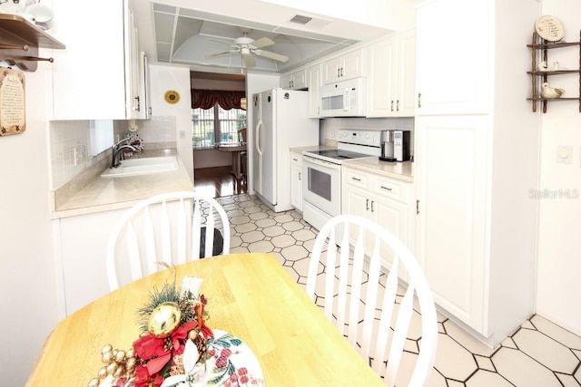 kitchen with white appliances, light countertops, a sink, and white cabinetry