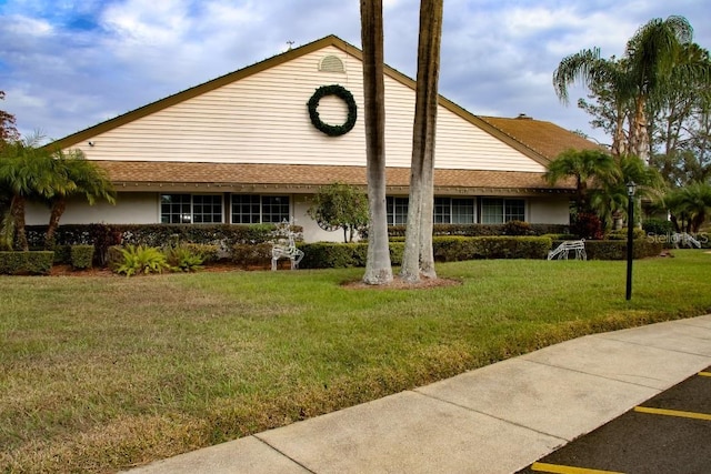 view of front of property with a shingled roof and a front yard