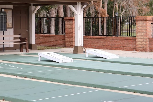 view of property's community featuring fence and shuffleboard