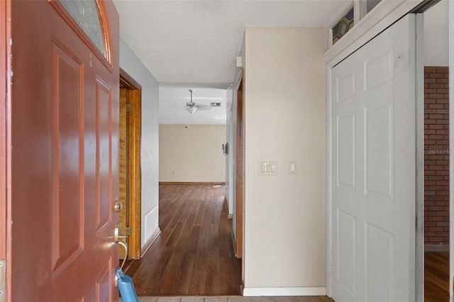 hall with hardwood / wood-style floors and a textured ceiling