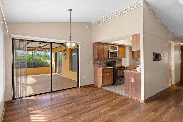 kitchen featuring tasteful backsplash, pendant lighting, high vaulted ceiling, light hardwood / wood-style floors, and black range with electric stovetop