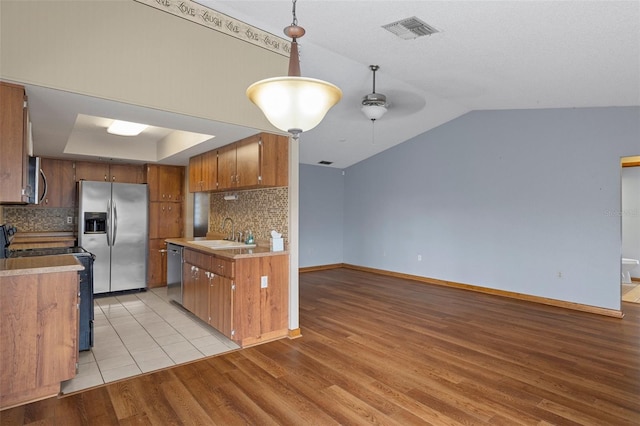 kitchen featuring decorative backsplash, appliances with stainless steel finishes, light wood-type flooring, ceiling fan, and sink