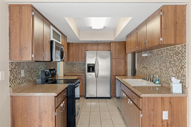 kitchen with sink, appliances with stainless steel finishes, tasteful backsplash, a tray ceiling, and light tile patterned flooring