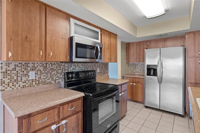 kitchen featuring a raised ceiling, light tile patterned floors, stainless steel appliances, and tasteful backsplash