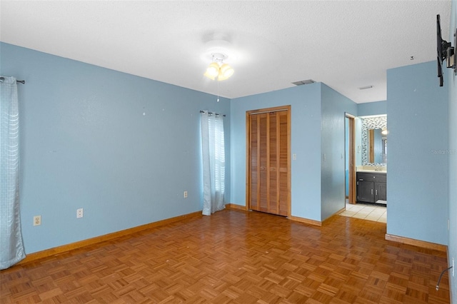 interior space featuring ensuite bathroom, light parquet flooring, and a textured ceiling