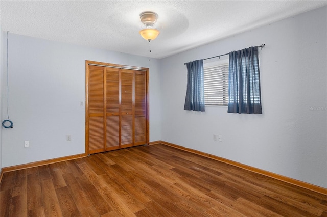 unfurnished bedroom featuring ceiling fan, a closet, a textured ceiling, and hardwood / wood-style flooring