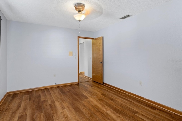 unfurnished room with hardwood / wood-style floors and a textured ceiling