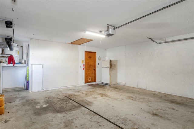 garage featuring white fridge and a garage door opener